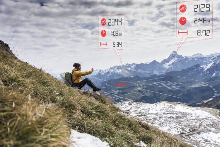 Mann blickt von Berg auf Daten, die aus seinem Smartphone projiziert werden