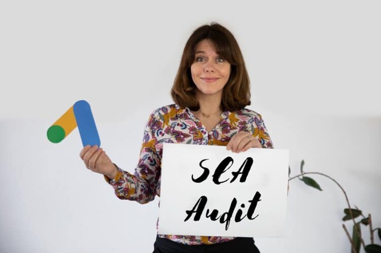 Frau mit Schild „SEA Audit“ und Google Ads Symbol in der Hand